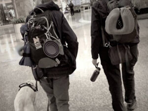 Two NATIONAL Crisis Response Canine teams walking through airport with dog at their side and backpacks laden with gear.