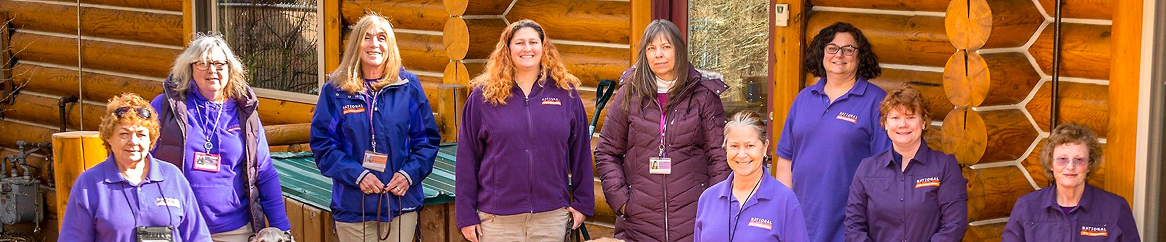 Volunteers with National Crisis Response Canines in front of a cabin.