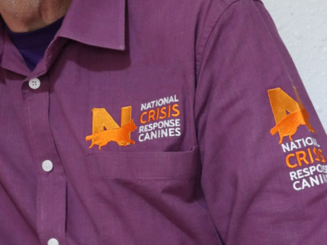 Close up of a volunteer's shirt, showing the NATIONAL Crisis Response Canines logo.