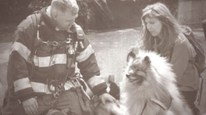911 Firefighter pets a crisis response canine, next to NCRC founder Cindy Ehers.