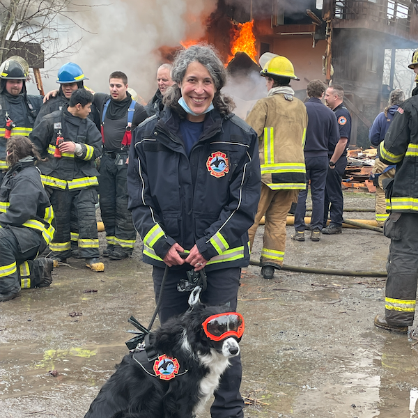 Embedded Crisis Response Canine team in Fire Department during an active fire training exercise. Canine is a border collie with protective goggles on.