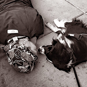 Trauma nurse laying on floor, nose-to-nose with a crisis response canine, a border collie.