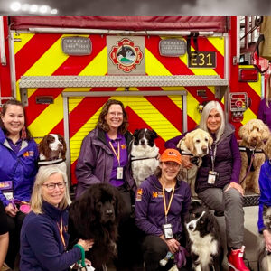 Group of NATIONAL Crisis Response Canine teams gathered around a fire truck at the Orcas Island Fire Station.