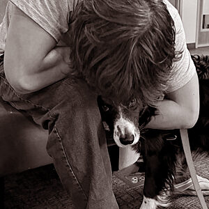 Homeless teen leaning over and hugging a crisis response canine, a border collie.