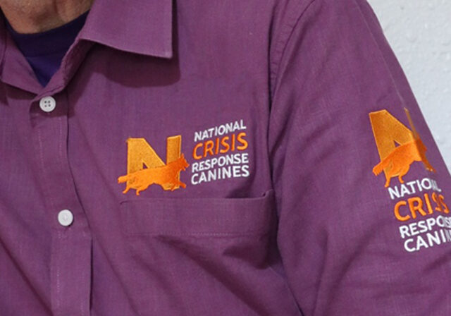 Close up of a volunteer's shirt, showing the NATIONAL Crisis Response Canines logo.